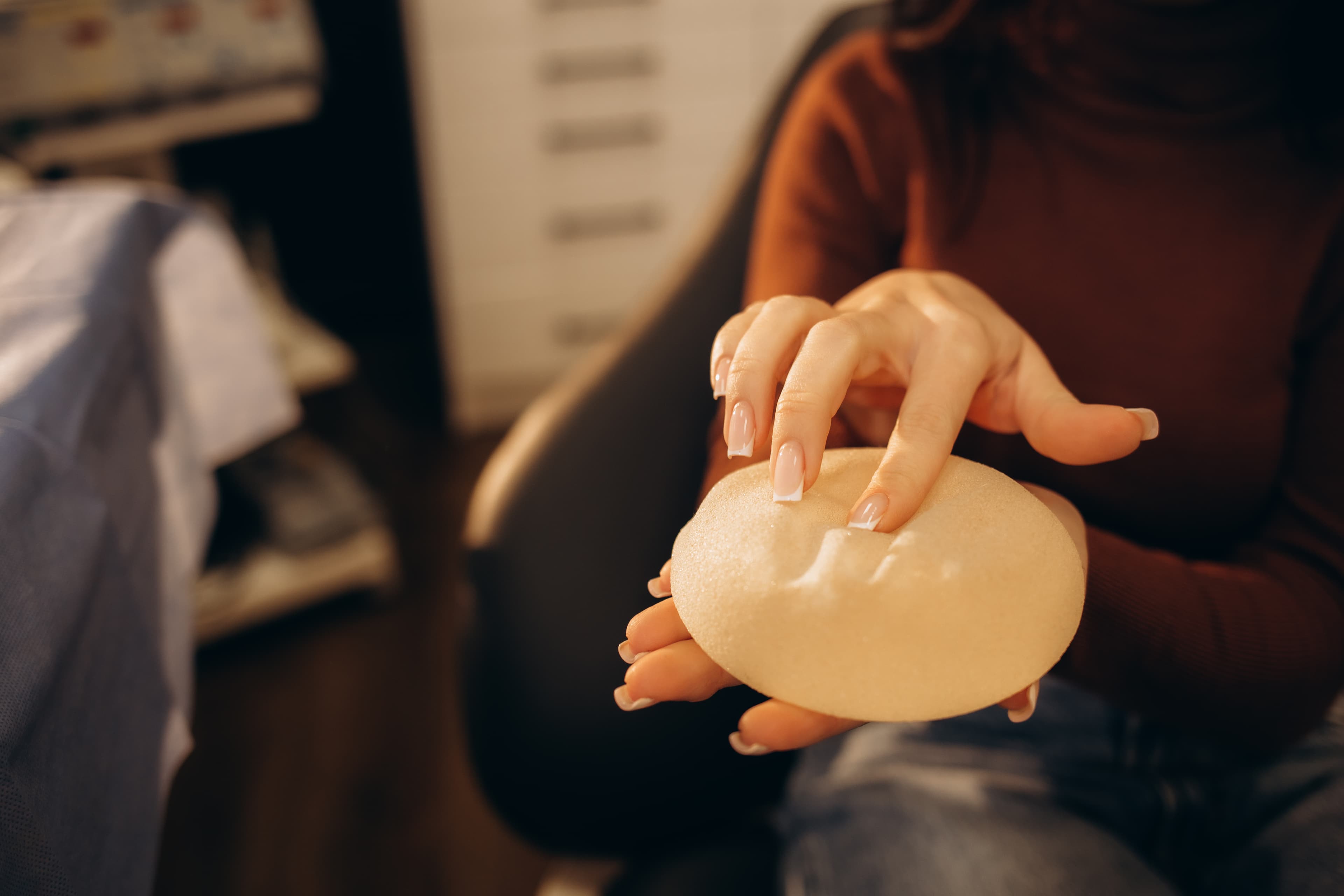 Woman holding a breast implant, illustrating treatment for capsular contracture